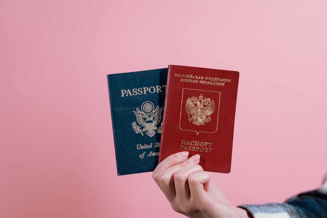 Crafting Captivating Headlines: Your awesome post title goes here Close-up of a hand holding American and Russian passports on a pink background.